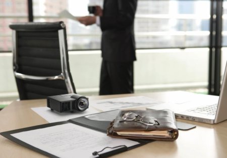 ricoh projecteur press posé sur un bureau. On constate qu'il est aussi grand qu'une paire de lunette